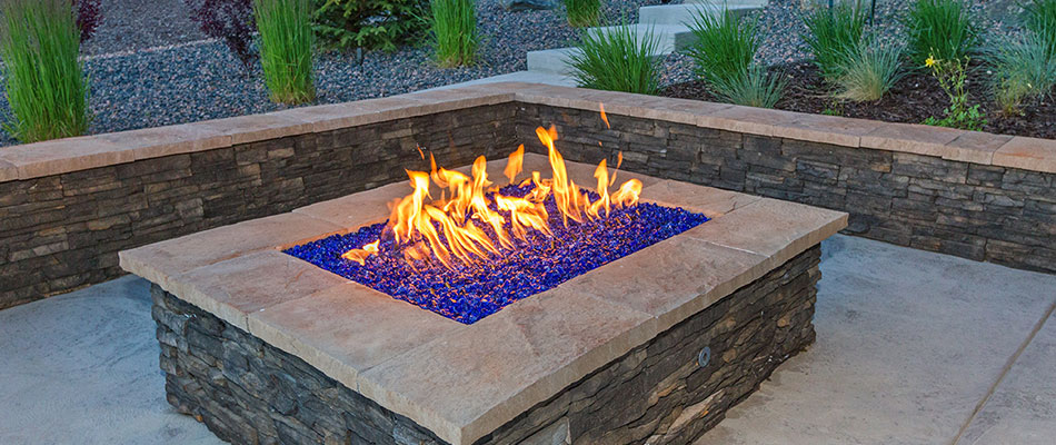 Gas-burning fire pit with blue rocks on custom patio near Exton, PA.