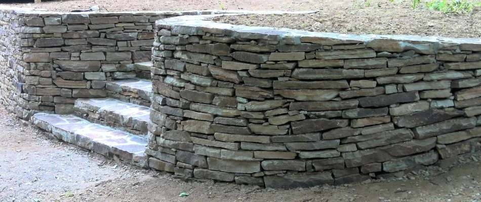 Natural stone retaining wall in West Chester, PA, with outdoor steps.