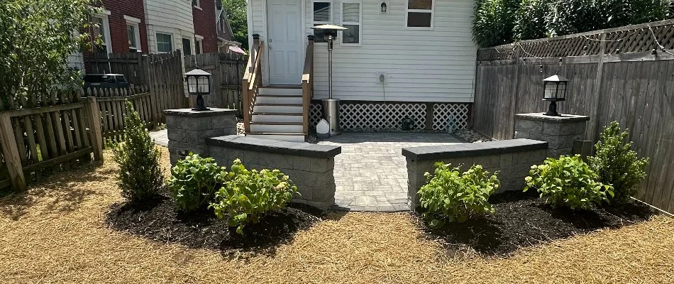 Sun shining on a landscape bed in West Chester, PA, beside a seating wall.