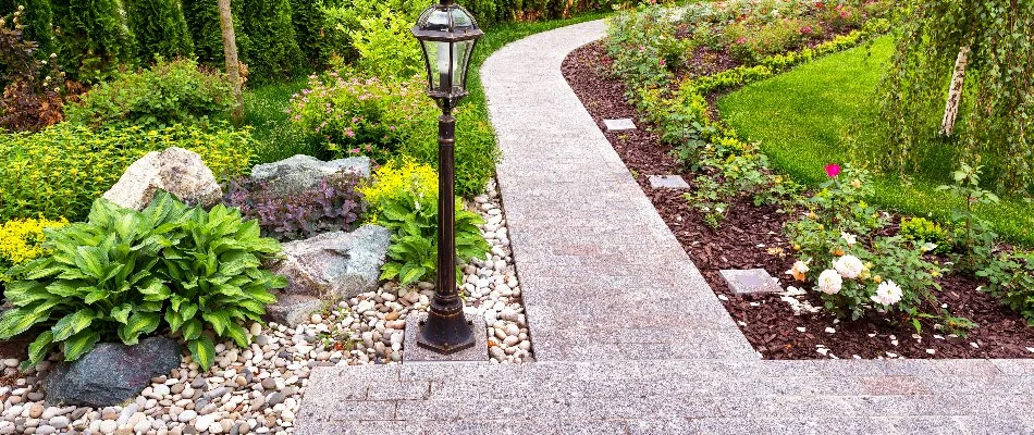 Walkway between landscape areas in West Chester, PA, with mulch, rocks, and plants.