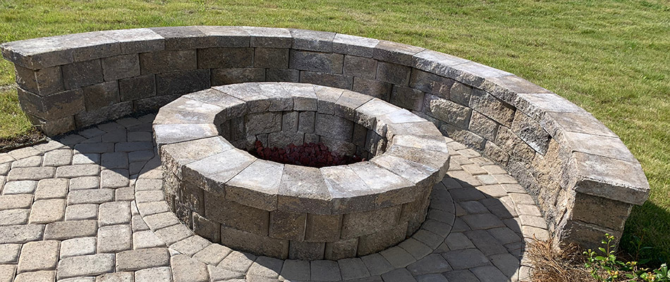 A stone fire pit with a custom seating wall installed around it in Malvern, PA.