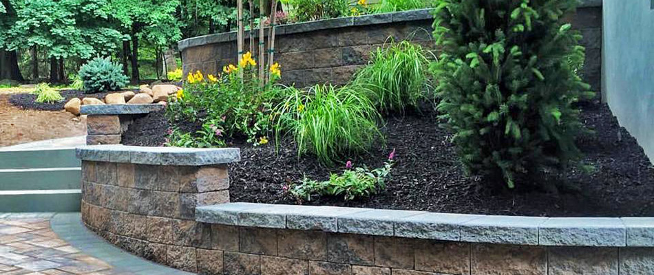 A stone retaining wall alongside a paved walkway near a home in Chester Springs, PA.